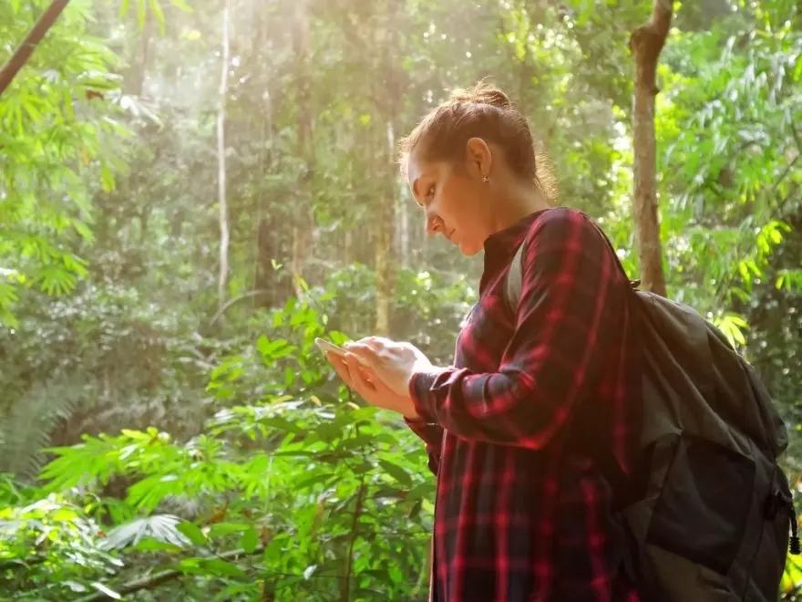 Lady wearing backpack and button down shirt in the rainforest