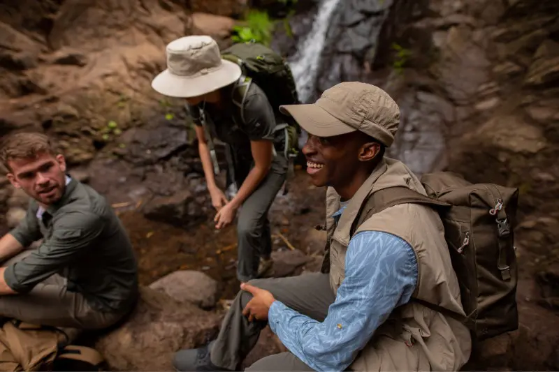 Three people wearing Craghoppers clothes in a humid country, infront of a waterfall